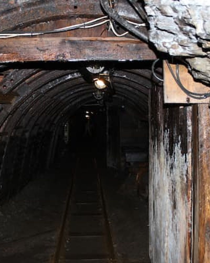 Entrance to an old underground mine shaft with timber framing and rail tracks
