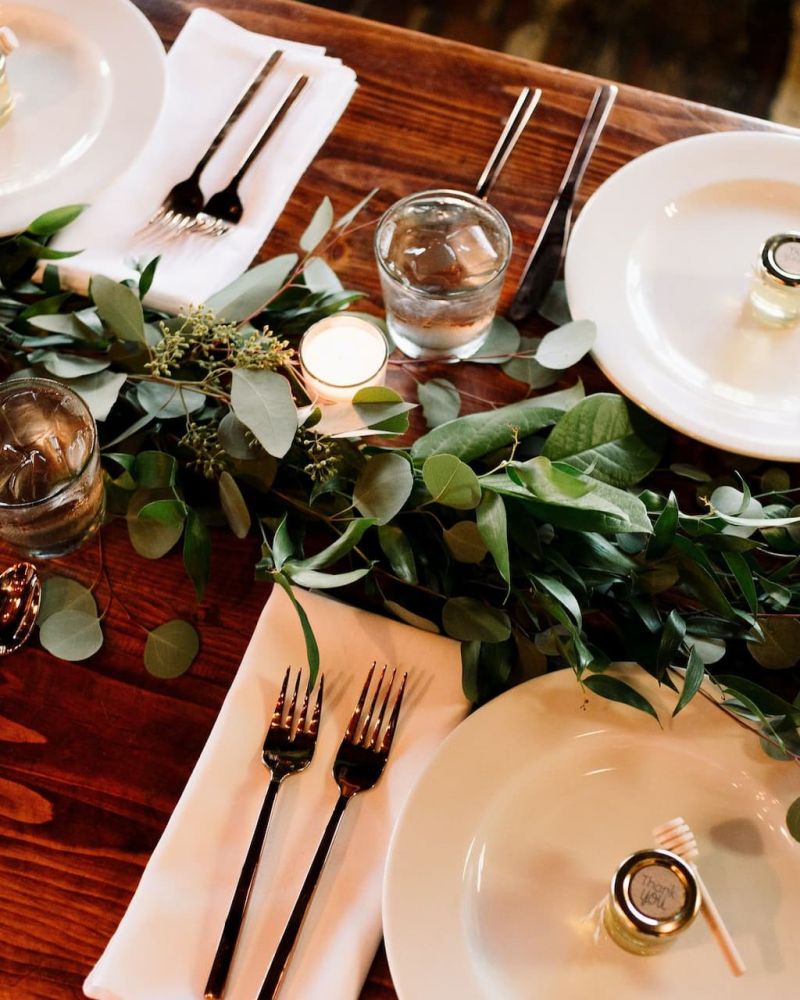Overhead view of a Thanksgiving table with eucalyptus garland and place settings