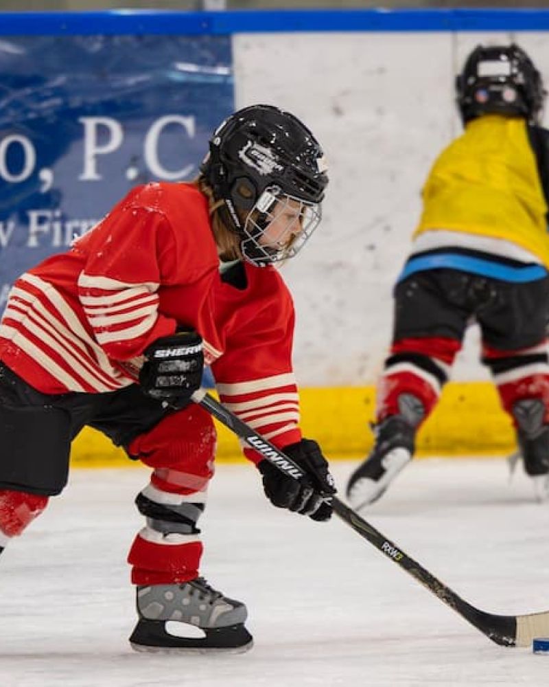 Youth hockey player in red jersey handling the puck during a rink scrimmage