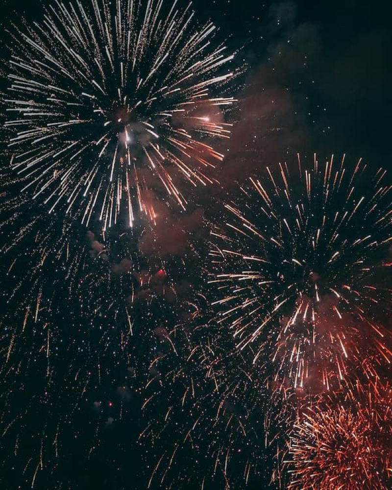 Fireworks bursting white and red against a dark night sky