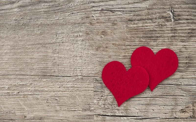 Two red felt hearts on a weathered wood background for Valentine's Day
