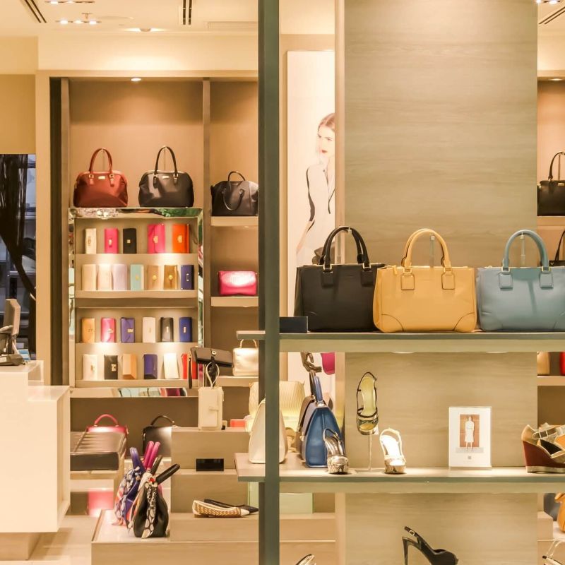 Boutique interior with handbags, wallets, and shoes on lit display shelves