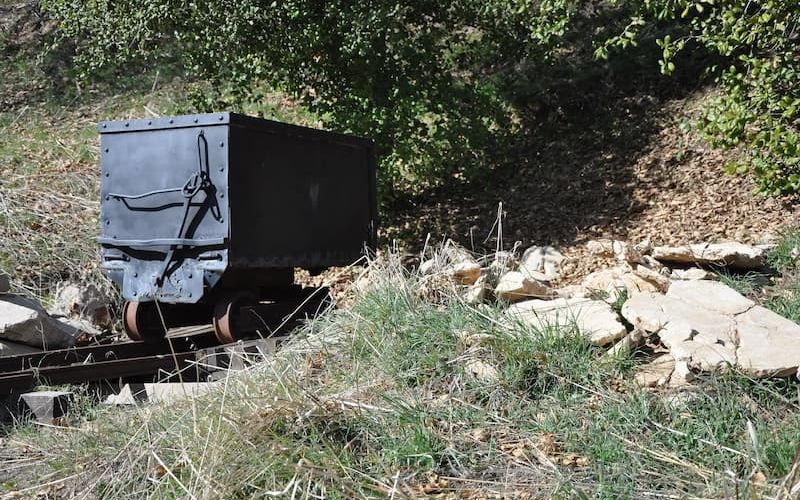 Old mining ore cart on rails along a hillside trail